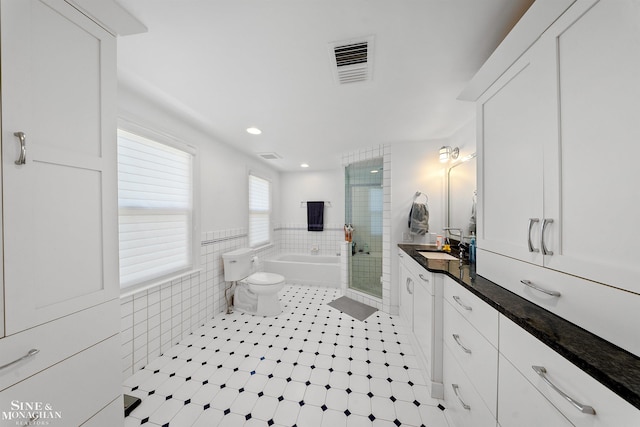 bathroom with vanity, tile walls, a shower stall, visible vents, and a bath