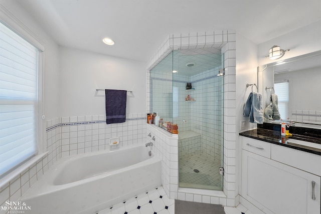 full bathroom featuring plenty of natural light, a garden tub, a stall shower, and vanity