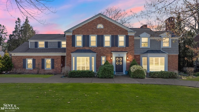 view of front of property with a lawn and brick siding