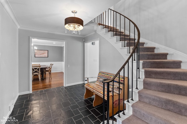 stairway with an inviting chandelier, baseboards, ornamental molding, and stone finish flooring