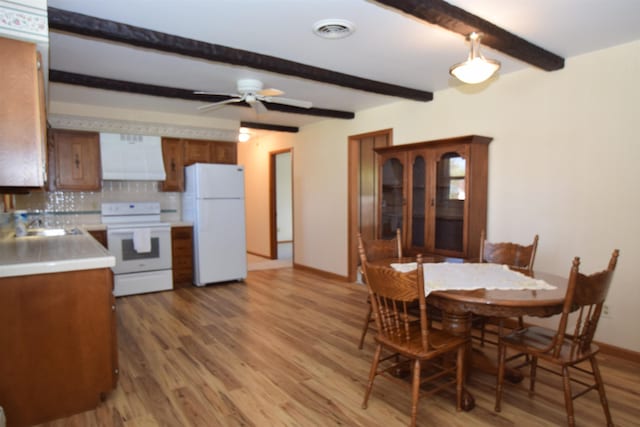 dining space featuring beam ceiling, a ceiling fan, baseboards, light wood-type flooring, and visible vents