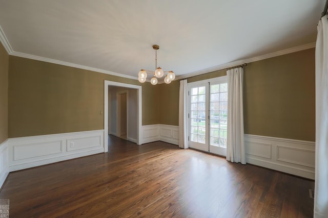 unfurnished dining area featuring wainscoting, dark wood-style floors, a notable chandelier, ornamental molding, and a decorative wall