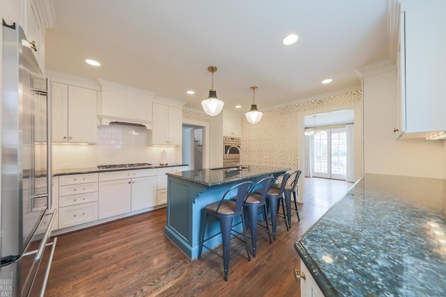 kitchen with crown molding, dark wood-style flooring, white cabinets, dark stone countertops, and appliances with stainless steel finishes