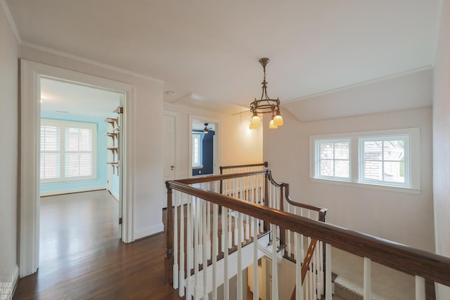 hall with dark wood-style flooring, baseboards, an upstairs landing, and a chandelier