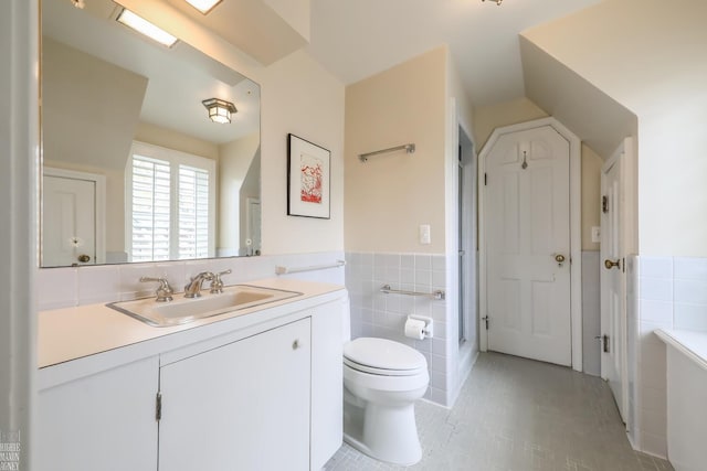 bathroom with wainscoting, vanity, toilet, tile patterned floors, and tile walls