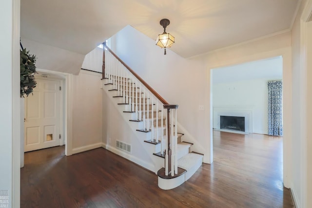 stairway featuring baseboards, visible vents, wood finished floors, and a fireplace