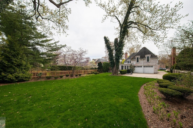 view of yard with an attached garage, fence, and driveway