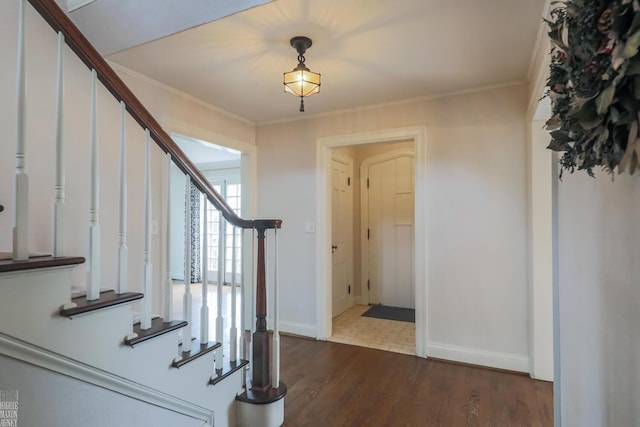 entrance foyer with baseboards, ornamental molding, stairs, and dark wood-style flooring