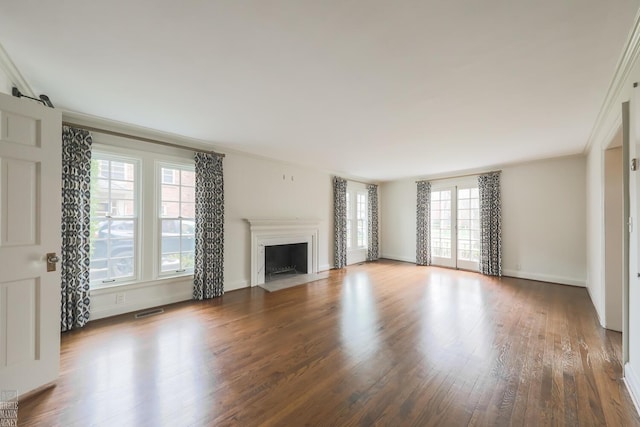 unfurnished living room featuring visible vents, a fireplace with flush hearth, crown molding, wood finished floors, and baseboards