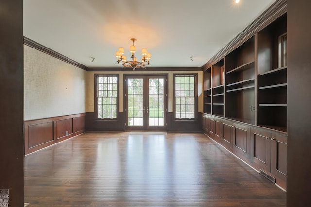 unfurnished dining area featuring crown molding, visible vents, an inviting chandelier, dark wood-style floors, and french doors
