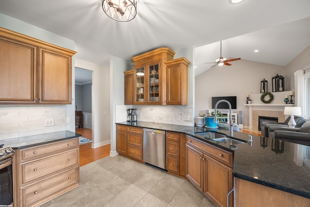 kitchen featuring appliances with stainless steel finishes, tasteful backsplash, a sink, dark stone countertops, and open floor plan