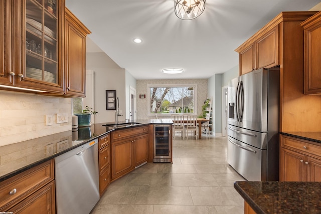 kitchen featuring beverage cooler, a sink, brown cabinetry, and stainless steel appliances