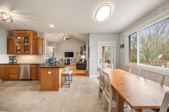 interior space with stainless steel dishwasher, brown cabinetry, a peninsula, a breakfast bar area, and a sink