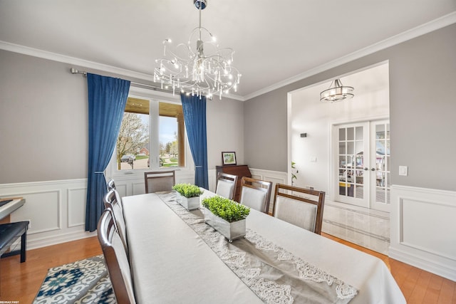 dining room with a chandelier, wainscoting, and wood finished floors