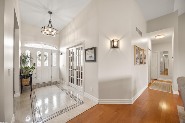foyer entrance with a notable chandelier, a high ceiling, visible vents, and baseboards