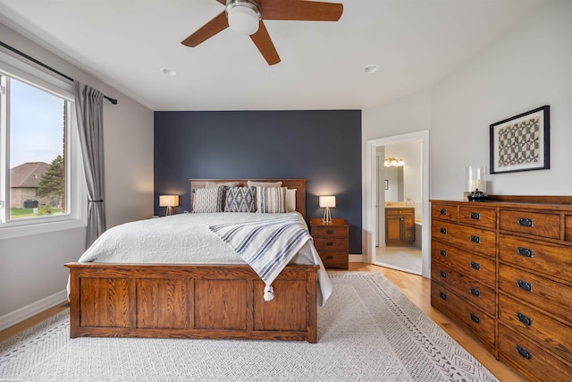 bedroom featuring connected bathroom, baseboards, ceiling fan, and light wood finished floors