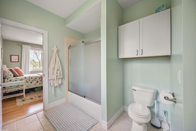 ensuite bathroom with shower / bath combination with glass door, toilet, tile patterned floors, baseboards, and ensuite bathroom