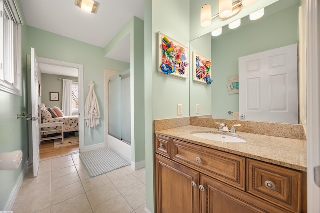 ensuite bathroom with connected bathroom, baseboards, tile patterned flooring, and vanity