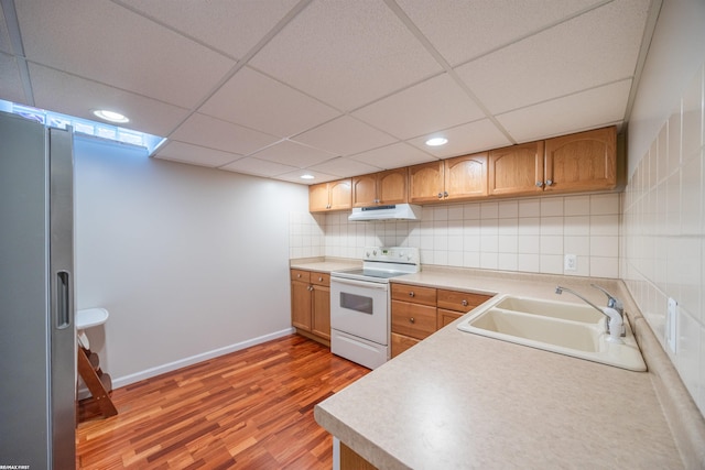 kitchen with light wood-type flooring, a sink, freestanding refrigerator, electric stove, and under cabinet range hood