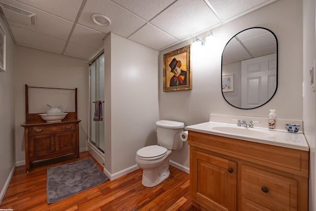 full bath with a drop ceiling, a stall shower, wood finished floors, and visible vents