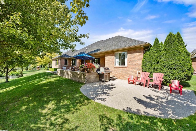 back of house with roof with shingles, a patio, a yard, and brick siding