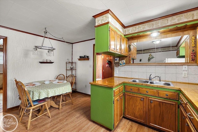 kitchen featuring crown molding, a sink, light wood-style floors, baseboards, and tasteful backsplash