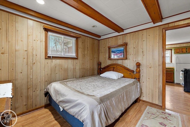 bedroom with freestanding refrigerator, wood finished floors, beam ceiling, baseboards, and wooden walls