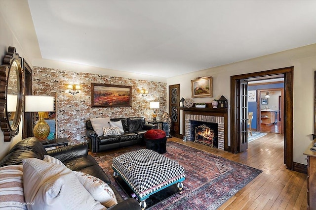 living area with wood-type flooring and a brick fireplace