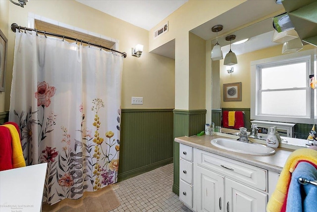 full bath featuring vanity, visible vents, a shower with shower curtain, and a wainscoted wall