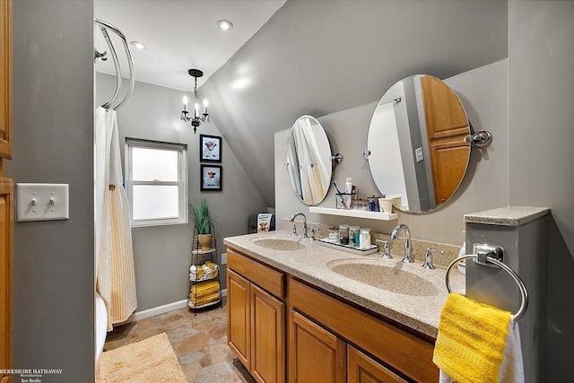 bathroom featuring double vanity, baseboards, vaulted ceiling, and a sink