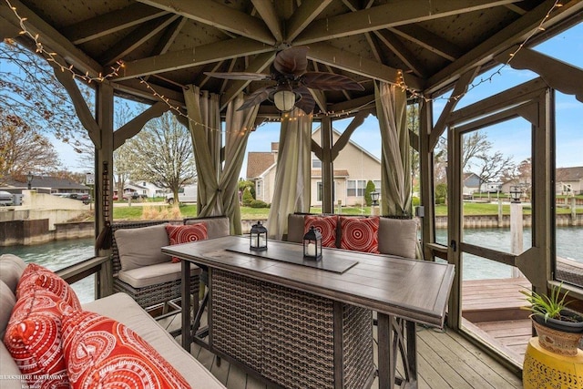 sunroom / solarium with a water view, ceiling fan, a residential view, and a wealth of natural light