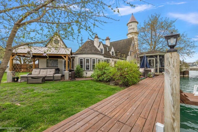 rear view of property with a lawn, a water view, a gazebo, and an outdoor living space