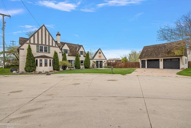 view of front of home featuring fence, a front lawn, a garage, stucco siding, and a chimney