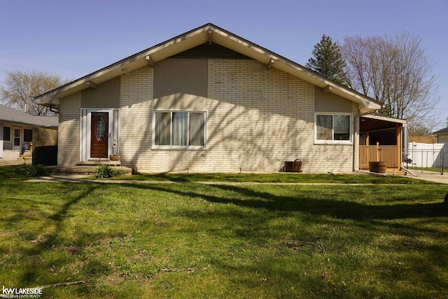 back of property featuring brick siding, a lawn, and entry steps