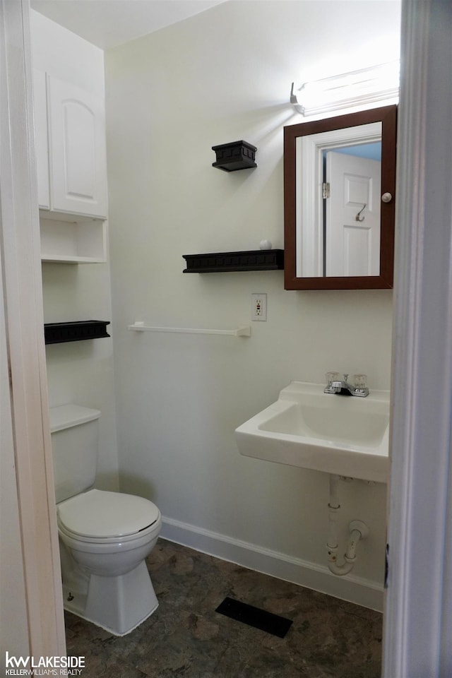 bathroom featuring a sink, baseboards, toilet, and visible vents