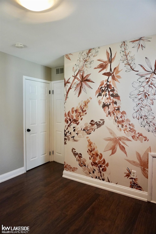 empty room with visible vents, dark wood finished floors, and baseboards