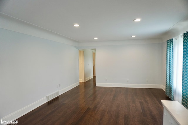 empty room featuring recessed lighting, baseboards, dark wood finished floors, and visible vents