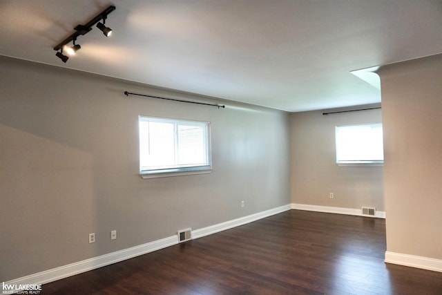 unfurnished room featuring baseboards, visible vents, track lighting, and wood finished floors