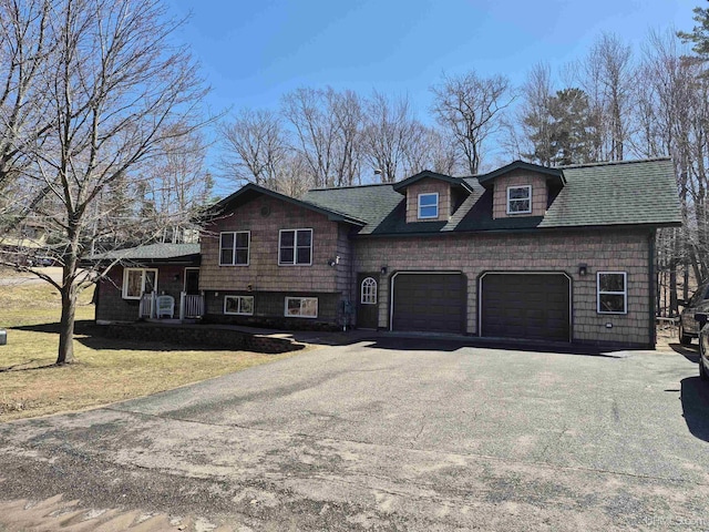 tri-level home with an attached garage, a shingled roof, and aphalt driveway