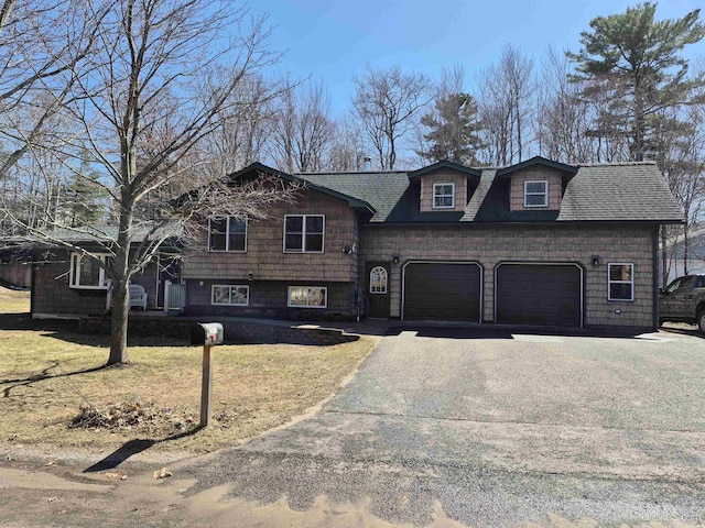 tri-level home featuring a garage, a shingled roof, a front lawn, and aphalt driveway