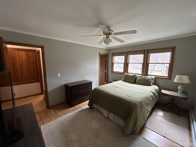bedroom featuring ceiling fan, light wood finished floors, baseboards, a baseboard radiator, and ornamental molding