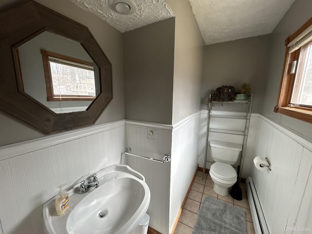 half bath with toilet, wainscoting, a sink, and a baseboard radiator