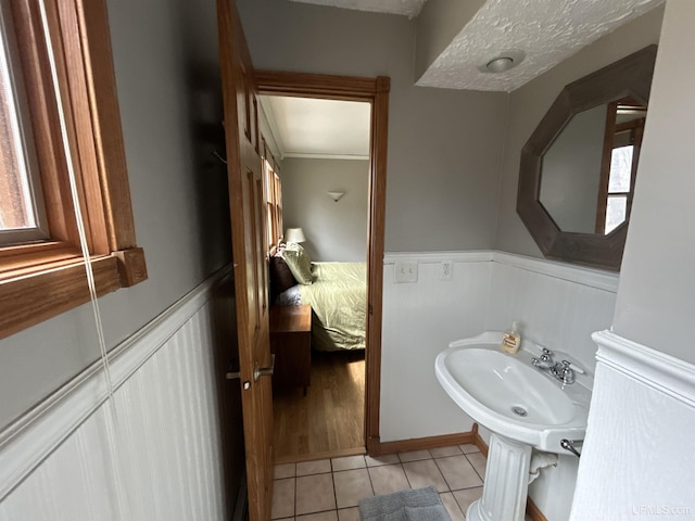 bathroom featuring tile patterned flooring, wainscoting, plenty of natural light, and a decorative wall