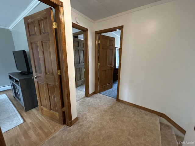 corridor featuring baseboards, ornamental molding, baseboard heating, and light colored carpet