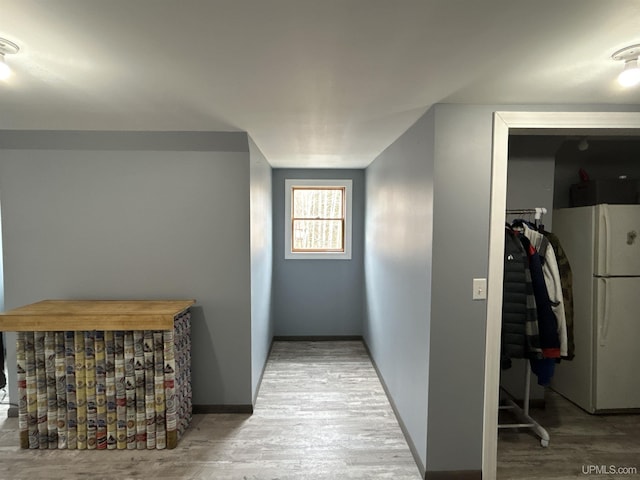 corridor featuring baseboards and wood finished floors