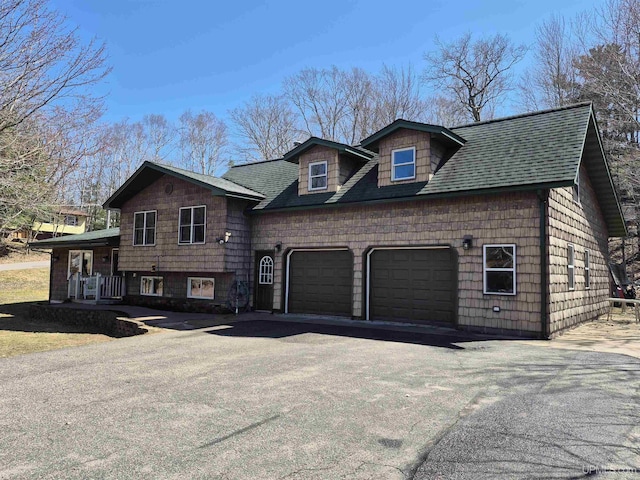 split level home featuring a garage, roof with shingles, and aphalt driveway