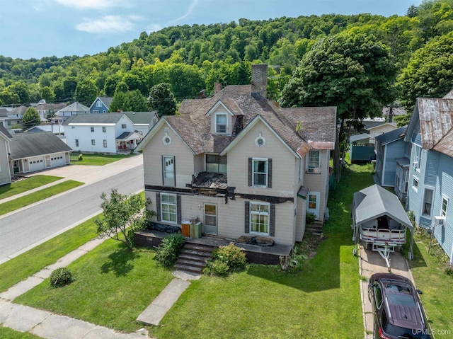 view of front of house with a wooded view, a residential view, a front yard, and a chimney