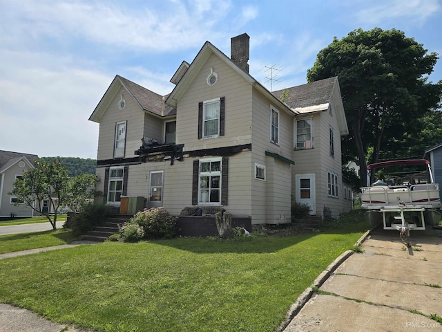 traditional-style home with a chimney, driveway, and a front yard