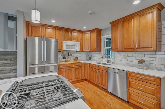 kitchen with a sink, brown cabinetry, stainless steel appliances, and light wood-style flooring