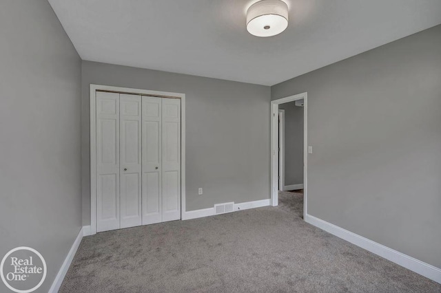 unfurnished bedroom featuring visible vents, carpet, baseboards, and a closet